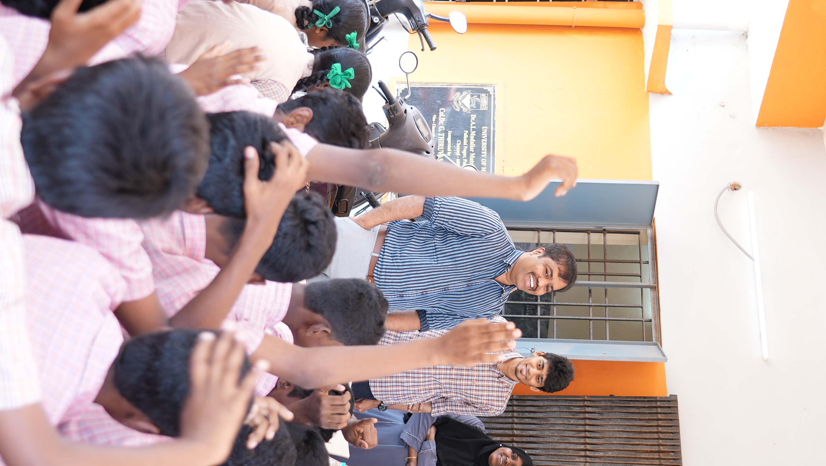 A volunteer shares a high-five with students lined up to greet the team