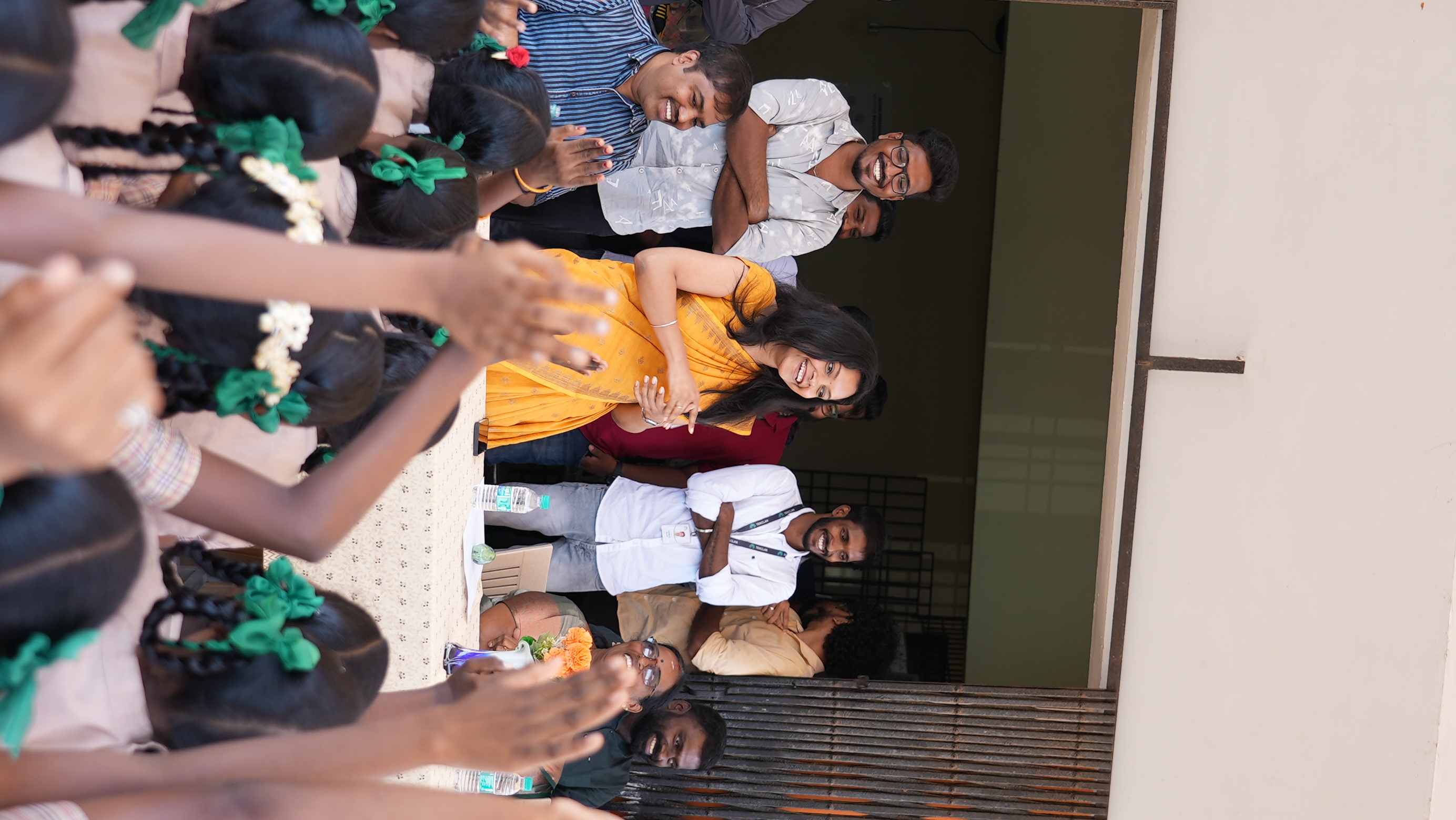 Students reach out to greet the team as they arrive at the school