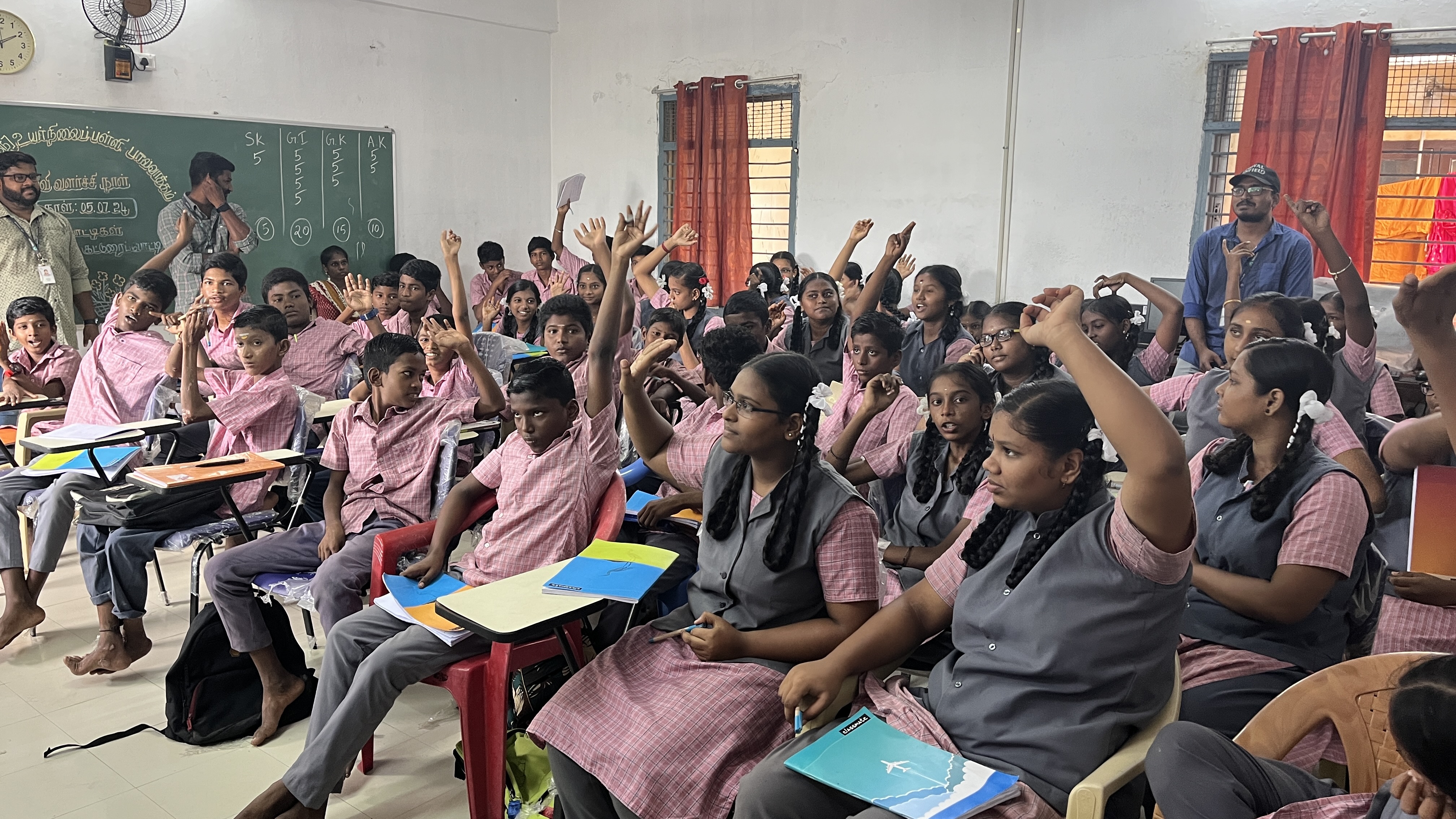 Students raise their hands to answer during a classroom quiz